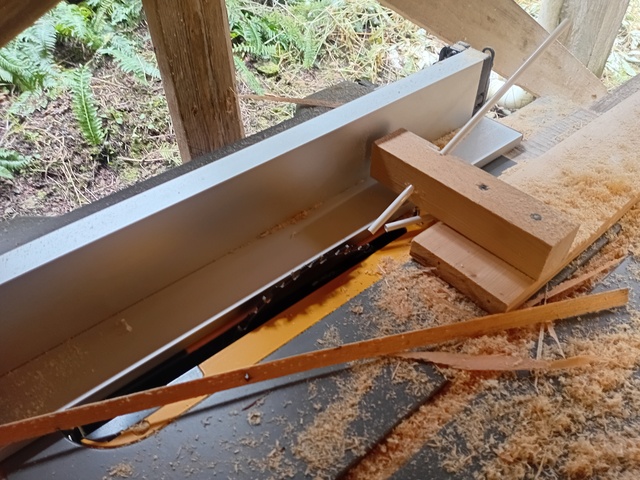 Close-up of dual plastic tubes through holes in wooden blocks used to keep the work flush with the table saw bed and the fence