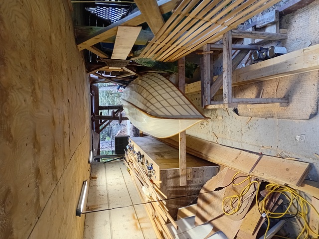 Picture of the skinned boat back under the porch with a coat of varnish still drying